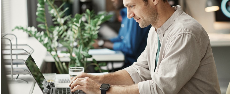 Man smiling and typing on computer