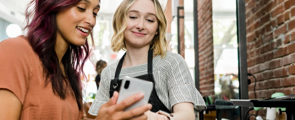 Two women smiling and looking at phone
